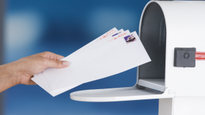 hand placing a postcard into a mailbox